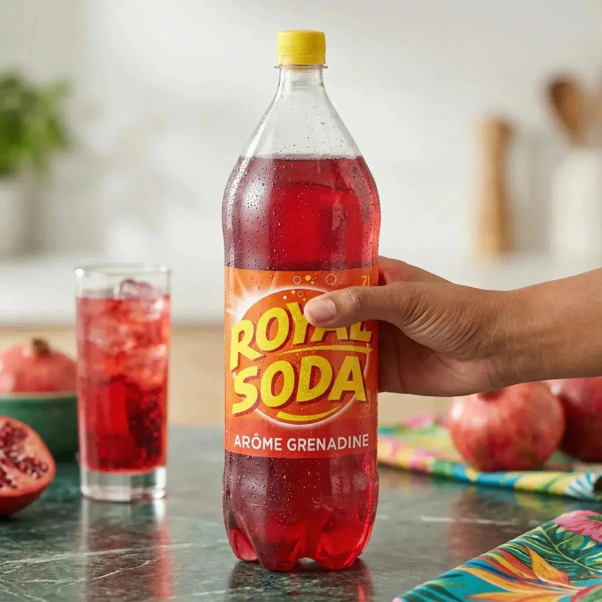 Botella de refresco ROYAL SODA sabor granadina (2L), vaso lleno, granadas.