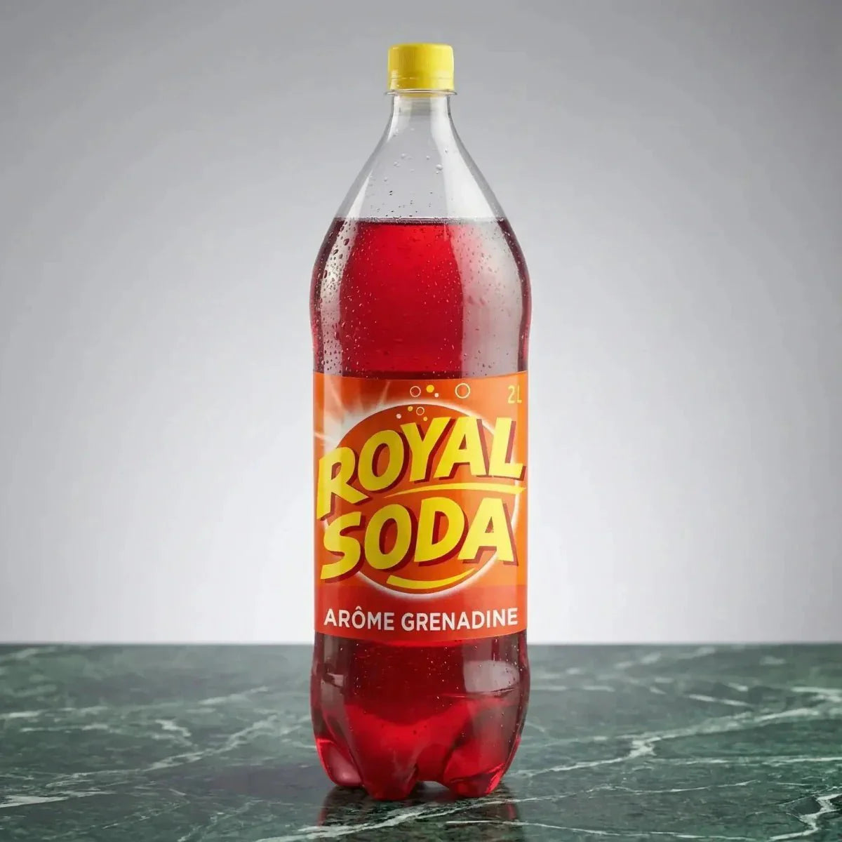 Botella de Royal Soda de granadina 2L sobre una mesa de mármol verde.