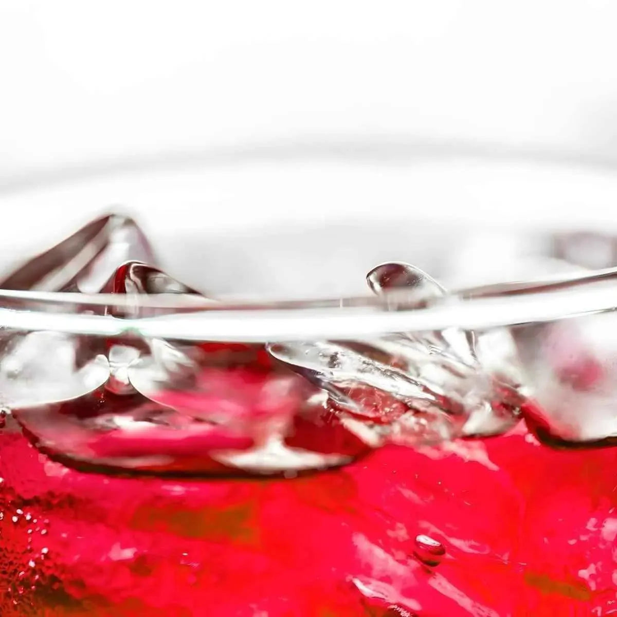 Gros plan sur un verre de soda goût grenadine TOP avec glaçons, boisson sucrée et rafraîchissante à la saveur intense.