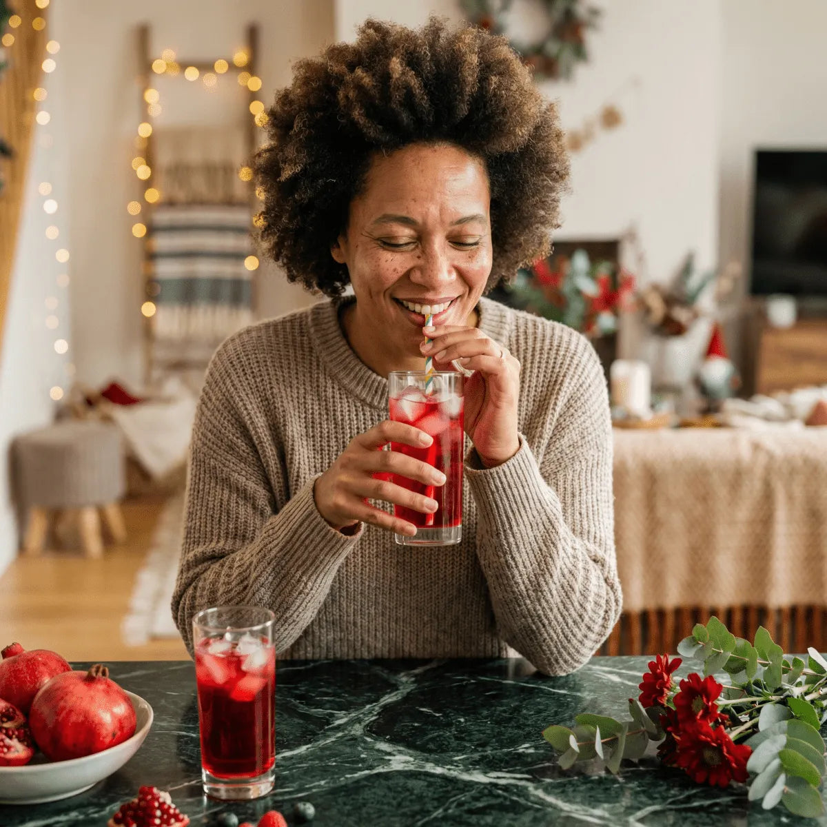 Una mujer sonriente bebe un refresco sabor granadina TOP en una escena festiva.