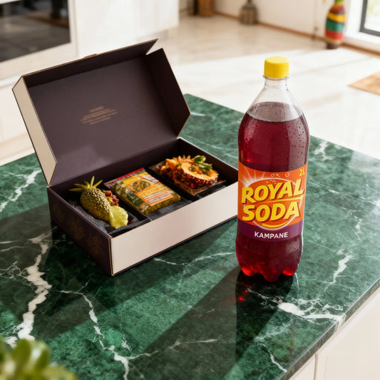 ROYAL SODA goût kampane 2L posé sur une table en marbre vert à côté d’un coffret repas, boisson parfaite pour accompagner vos plats.