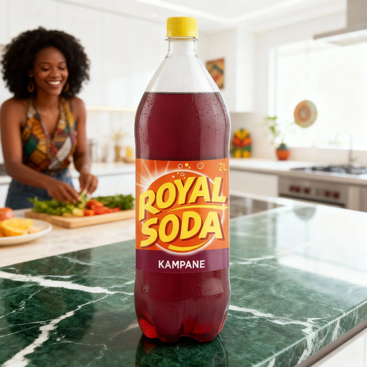 Boisson ROYAL SODA goût kampane 2L sur un plan de travail en cuisine, avec une femme préparant un repas en arrière-plan, ambiance conviviale.