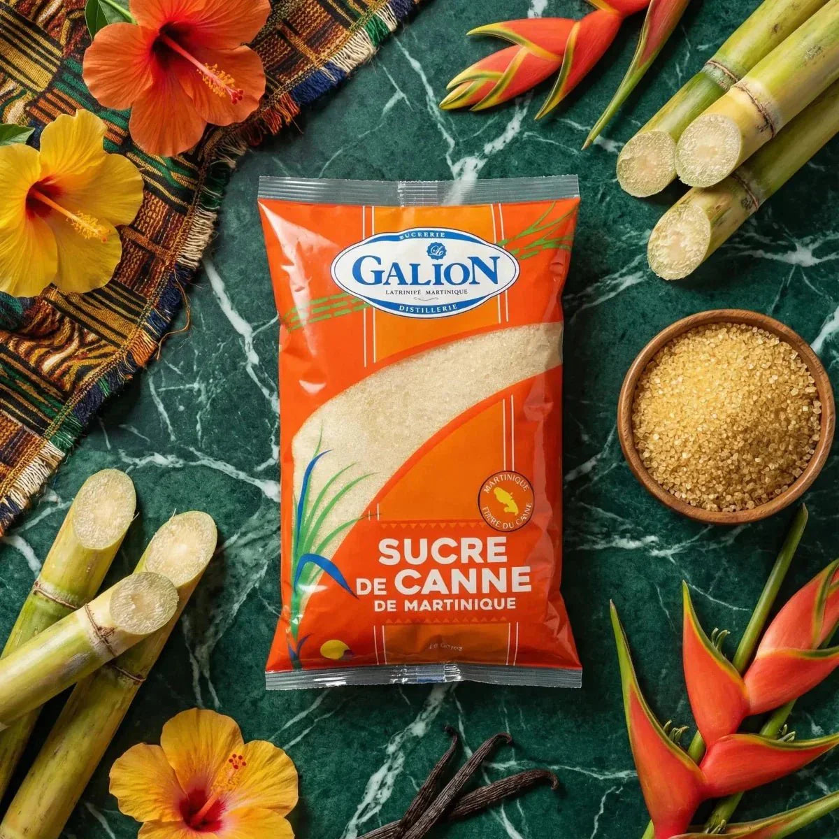 Sucre de canne LE GALION 1kg. Scène avec fleurs d'hibiscus, sucre roux en bol, tiges de canne.
