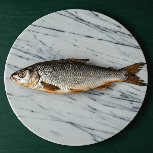 Tambour / Capitaine NANKA fumé - POISSON - NKOSI présenté sur une planche en marbre ovale, idéal pour la vente de poisson fumé surgelé premium.