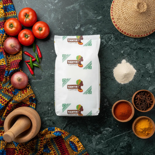 Fécule de pomme de terre TANTIE posée sur table avec épices, légumes et tissus africains, ingrédient sans gluten pour sauces et pâtisseries.
