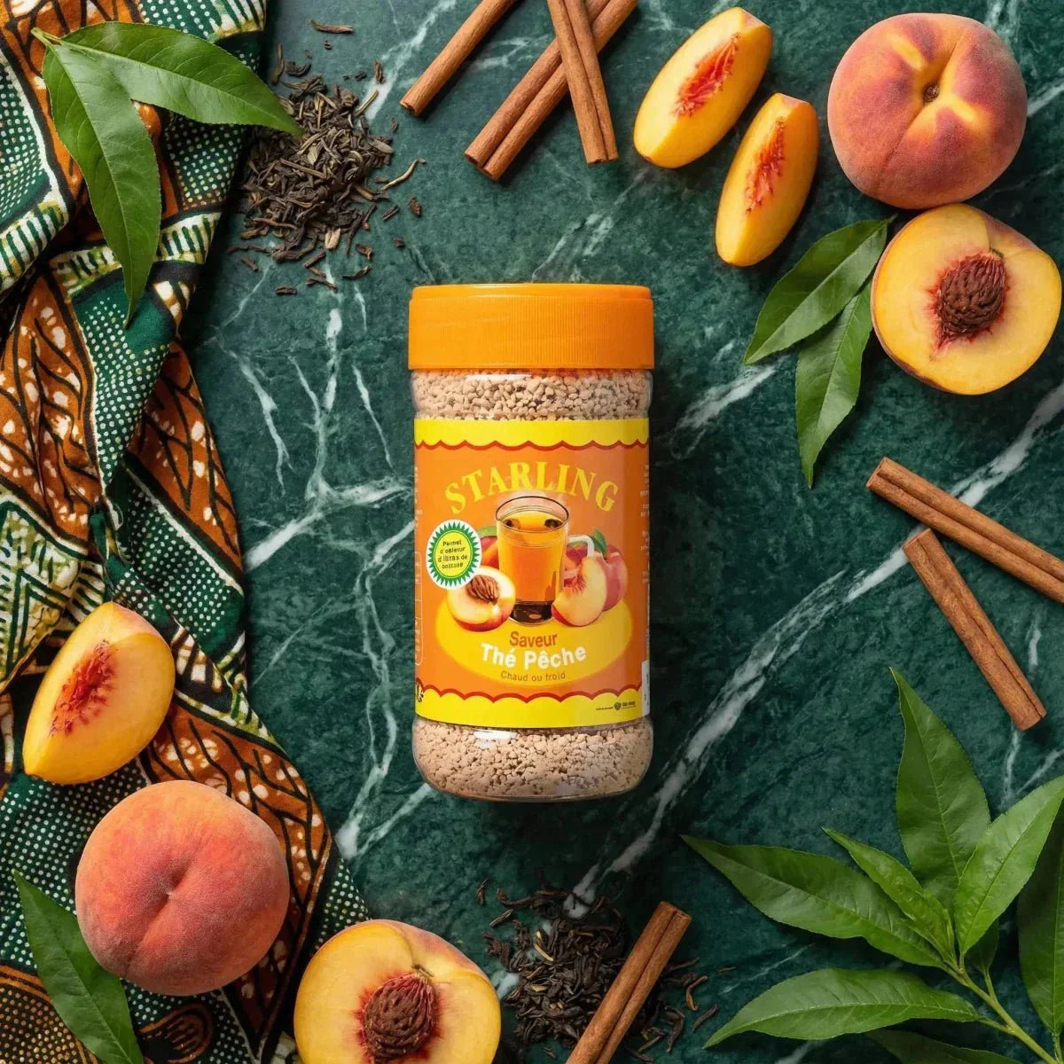 Instant perzikthee van Starling, met kaneelstokjes en groene bladeren.
