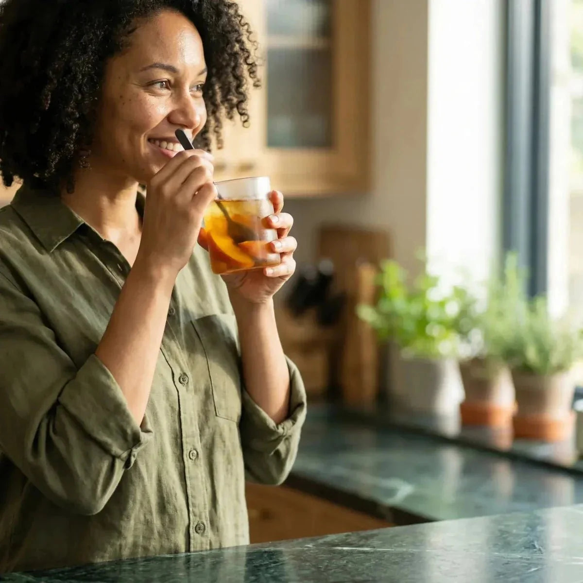 Perzikthee STARLING verkocht per set, vastgehouden in een zonnige keuken door een glimlachende vrouw.