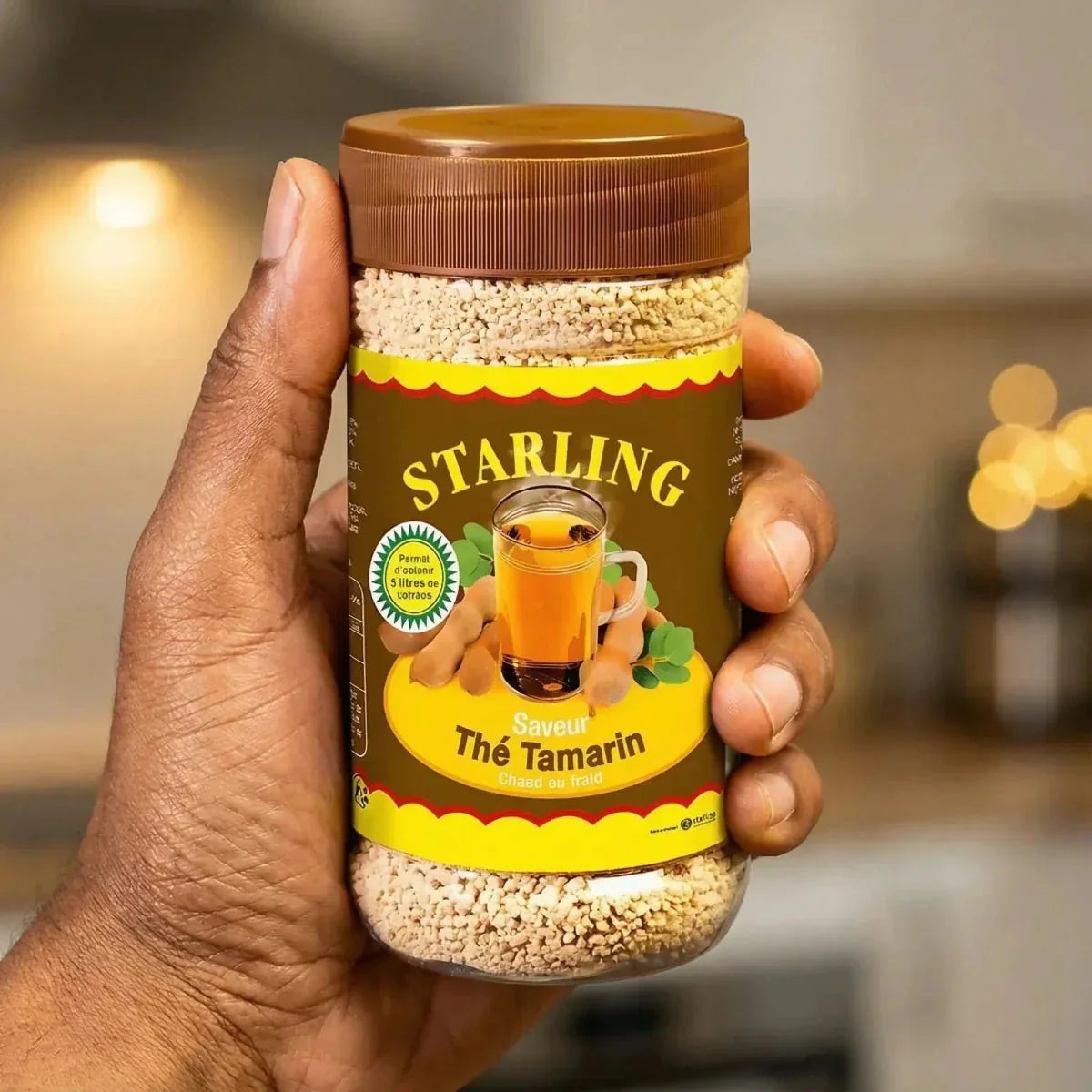 Tamarinden-Tee STARLING in einem Glas, das von einer Hand gehalten wird. Fokus auf dem Produktschild.