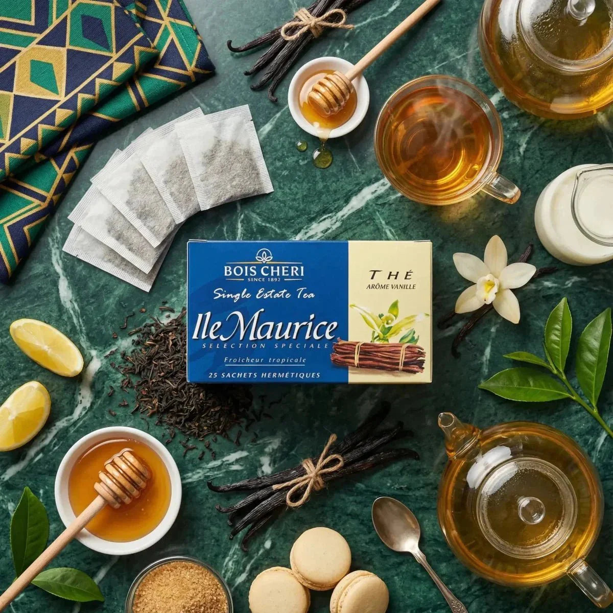 Vanillethee Bois Chéri op een marmeren tafel met theepot, kopje, honing, citroen, macarons.