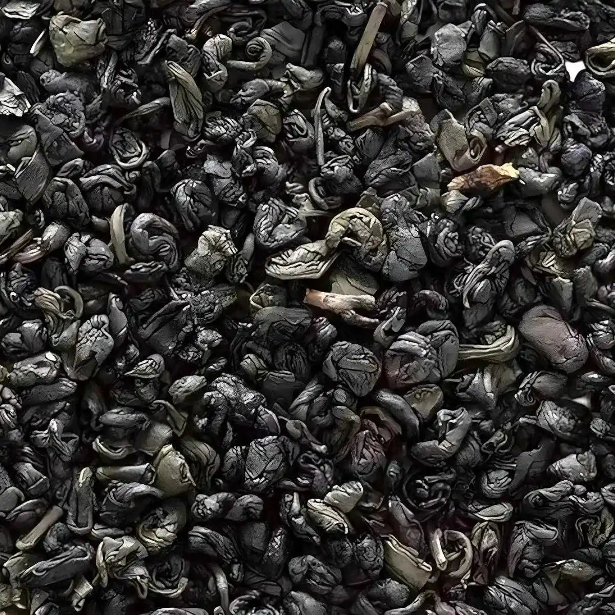 Gros plan sur feuilles roulées du thé vert Gunpowder Superextra 555, texture dense et qualité premium pour infusion intense.