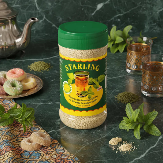 Thé Menthe Nanah STARLING posé sur une table en marbre avec verres à thé, menthe fraîche et pâtisseries orientales, ambiance détente et traditionnelle.