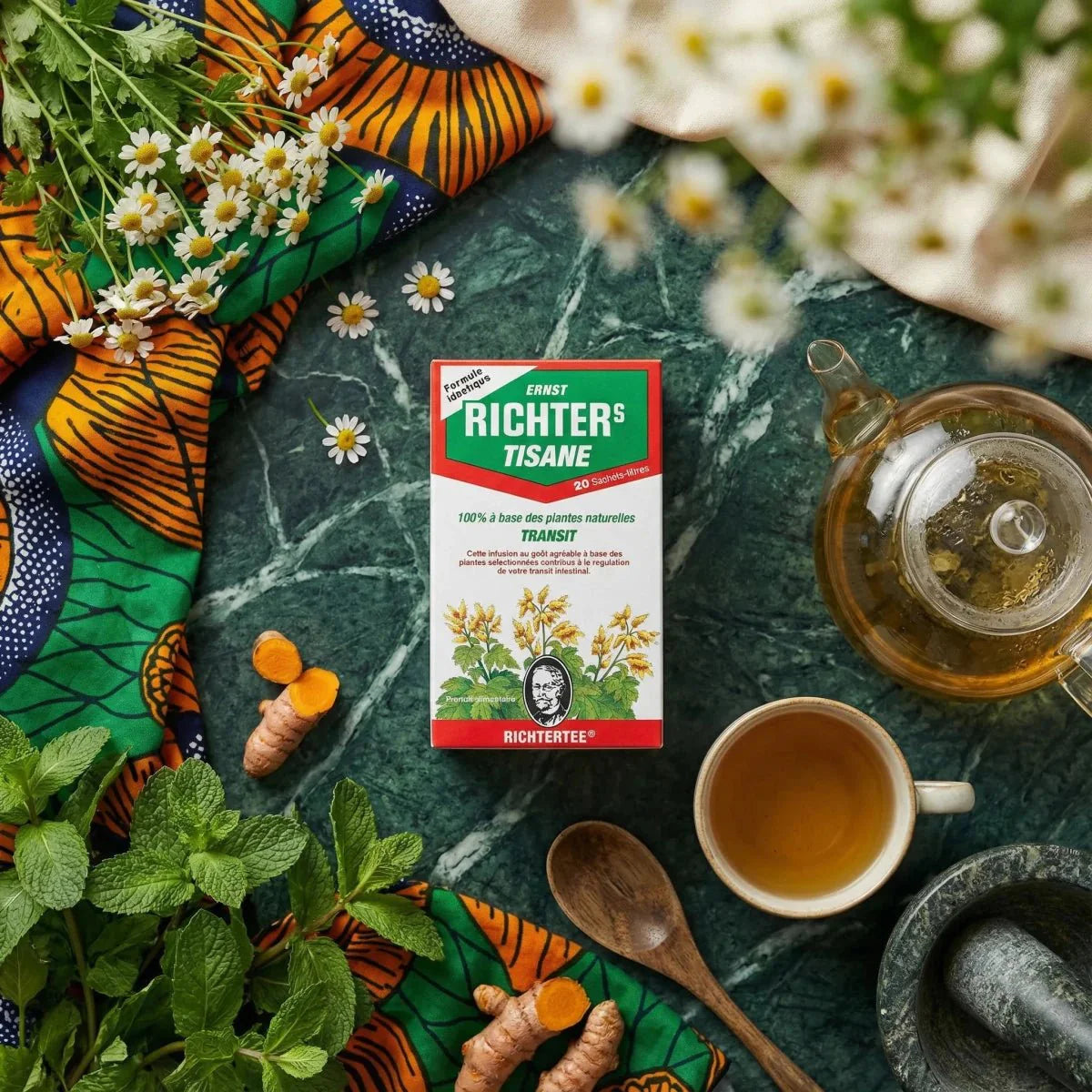 Thee Richter Kruidenthee Transit, stilleven met bloemen, munt, kurkuma, theepot en kopje.