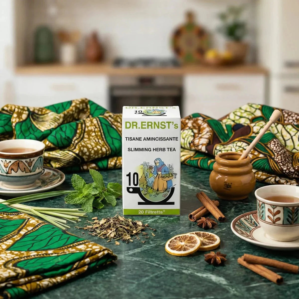 Afslankende kruidenthee DR ERNST. Theepakket op tafel met kopjes, kruiden, honing.