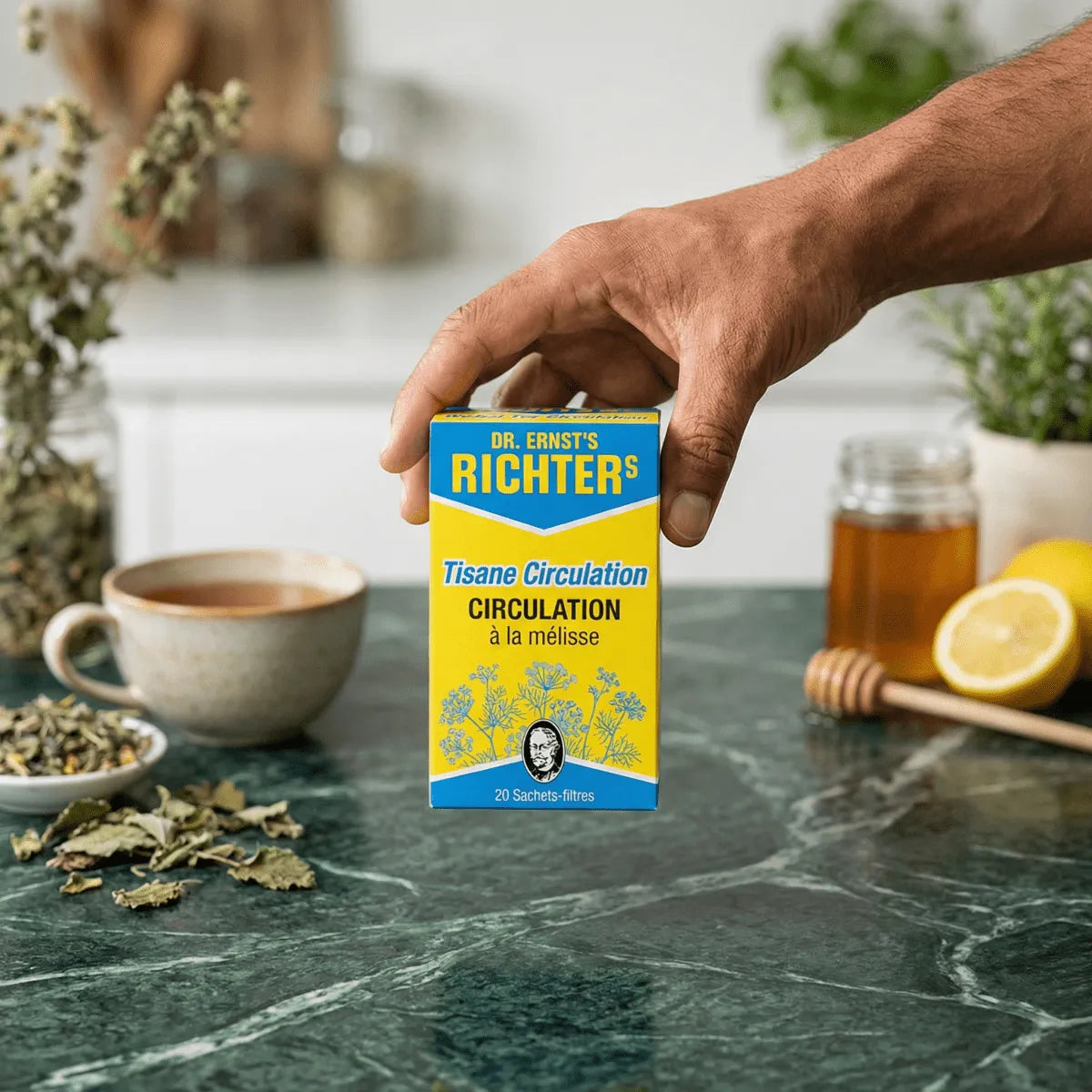 Tisane Circulatie van DR ERNST'S vastgehouden in een hand, op een tafel met een kopje thee en honing.
