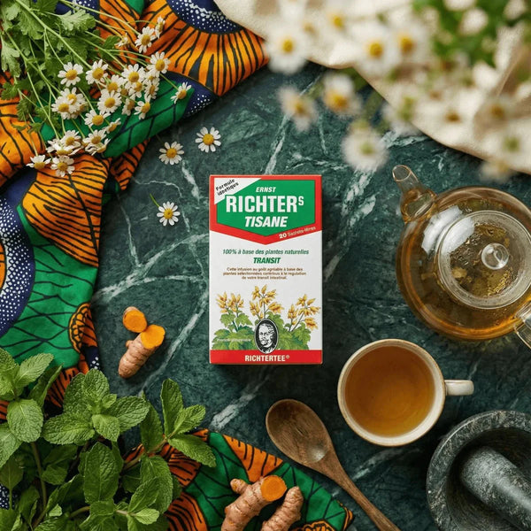 Tisane Transit de la marque RICHTER, dans un décor avec des fleurs, des épices et une théière.
