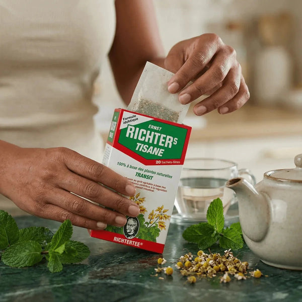 Tisane Transit RICHTER : une main sort un sachet de la boîte, sur une table avec théière.