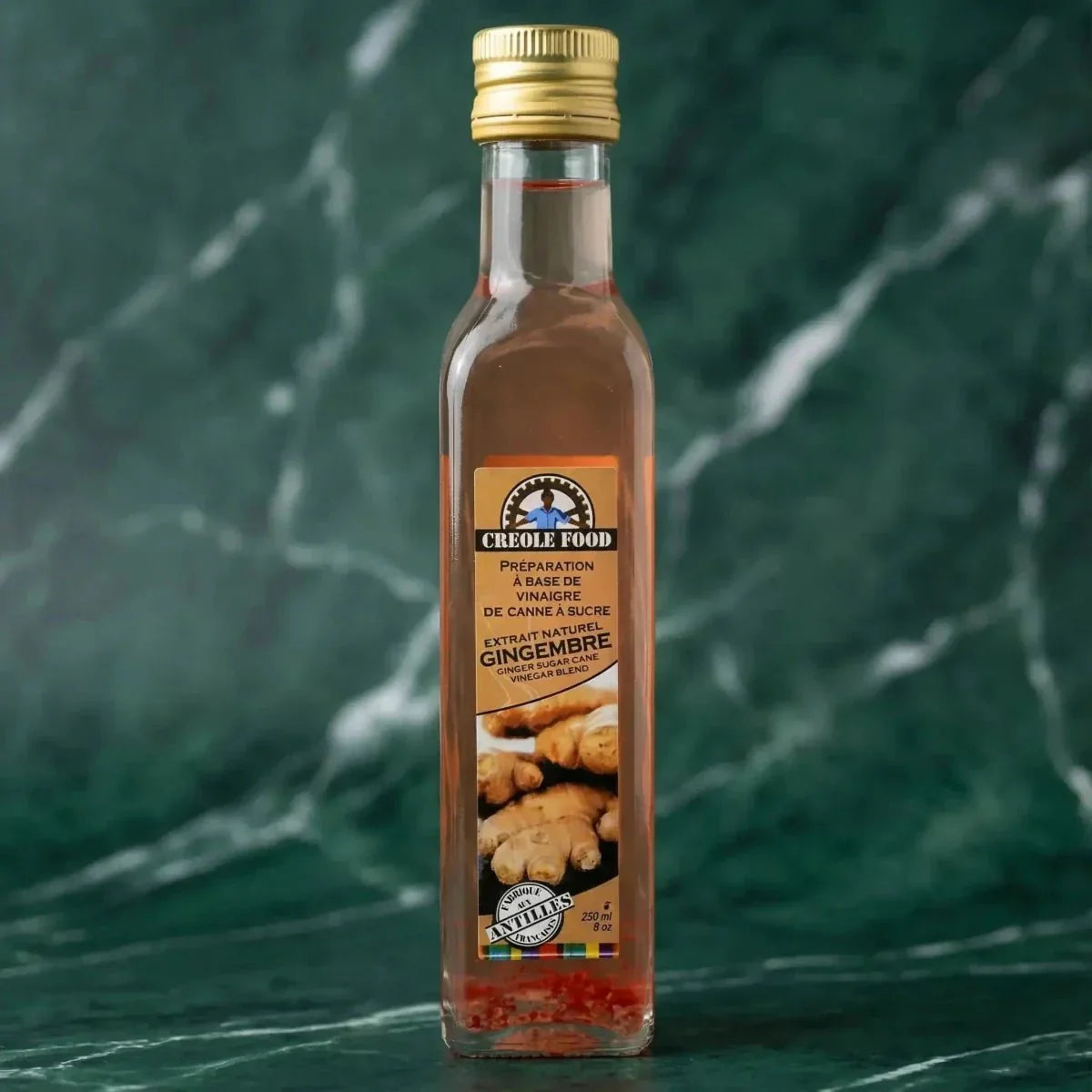 Bouteille de vinaigre de canne au gingembre CREOLE FOOD sur fond marbré vert : produit.