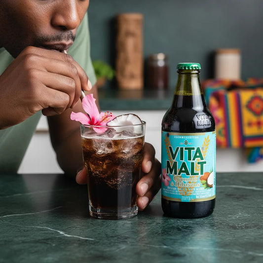 Homme dégustant la boisson VITA MALT Coco Hibiscus avec glaçons et fleur, boisson sans alcool au goût tropical unique.